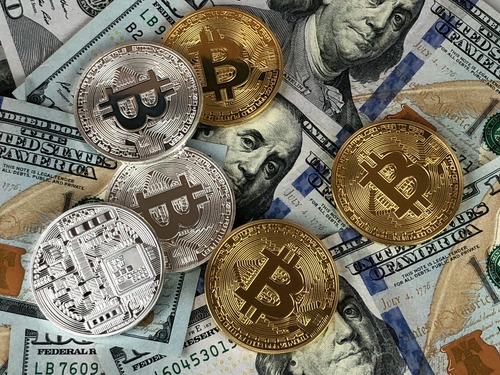 Gold and silver cryptocurrency coins placed on top of US dollar banknotes