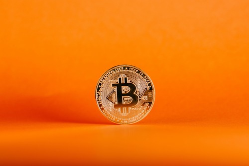 Bitcoin (BTC) cryptocurrency logo coin on an orange background