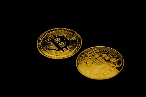 Two gold Bitcoin (BTC) cryptocurrency logo coins on a black background
